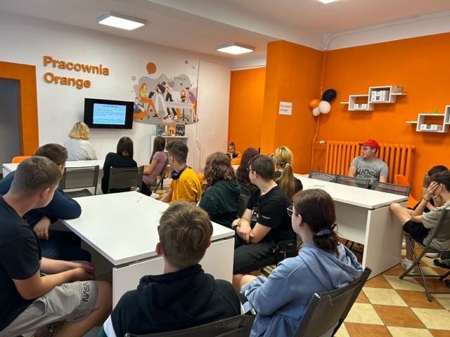 zdjęcie grupy młodzieży oglądającej kod do rozkodowania wiersza w pracowni orange