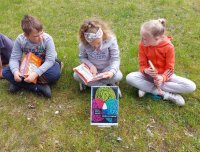 zdjęcie dzieci na trawie z książkami i plakatem