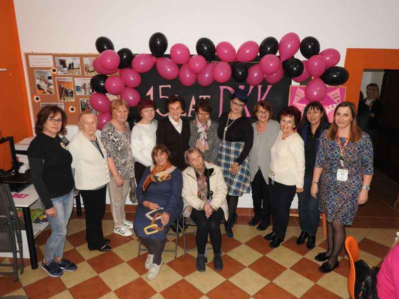 grupowe zdjęcie uczestniczek DKK wraz  z prowadzącymi grup oraz pisarką Agnieszką Lis na tle tablicy z napisem 15 lat DKK i balonami