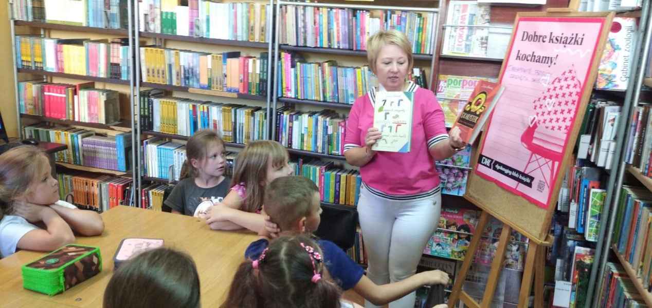 zdjęcie bibliotekarki opowiadającej dzieciom o książkach