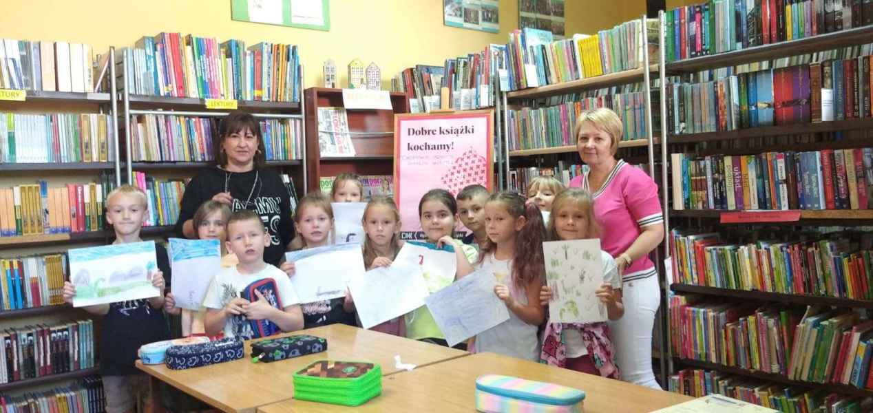 zdjęcie grupowe bibliotekarki oraz grupy bibliotecznej z wychowawczynią i pracami plastycznymi