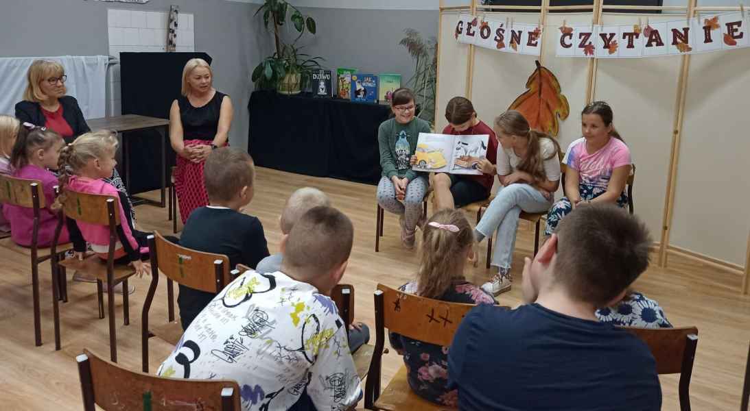 zdjęcie dzieci czytających książkę przed publicznością