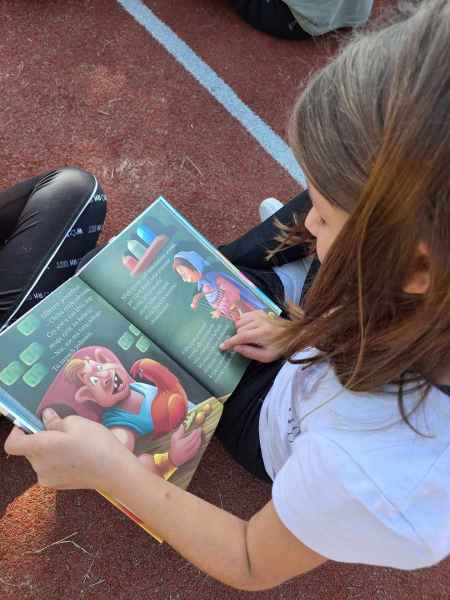 zdjęcie dziewczynki z rozłożoną książką podczas czytania 