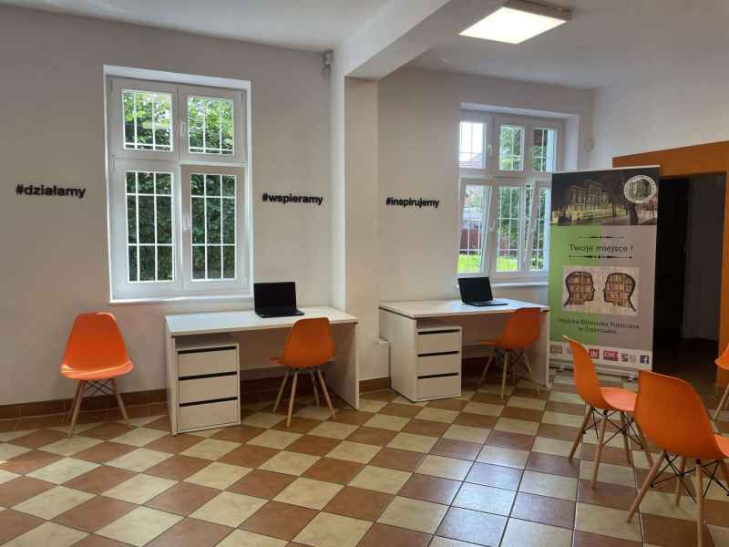 zdjęcie pracowni orange z widocznymi biurkami, laptopami, krzesłami i banerem biblioteki