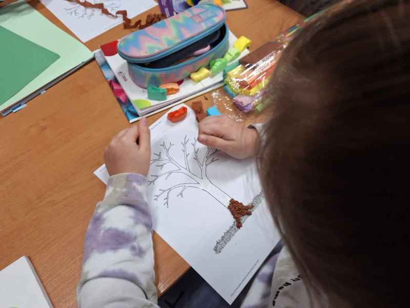zdjęcie dziecka w trakcie wyklejania rysunku drzewa bibułą