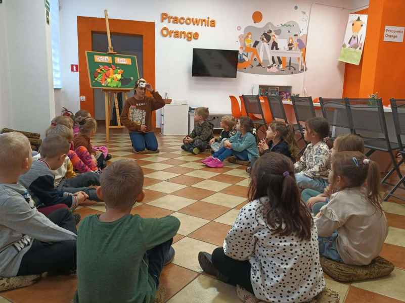 zdjęcie bibliotekarki i dzieci siedzących na podłodze w pracowni orange