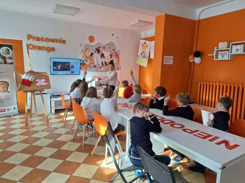 zdjęcie bibliotekarki oraz zgłaszających się dzieci w Pracowni Orange