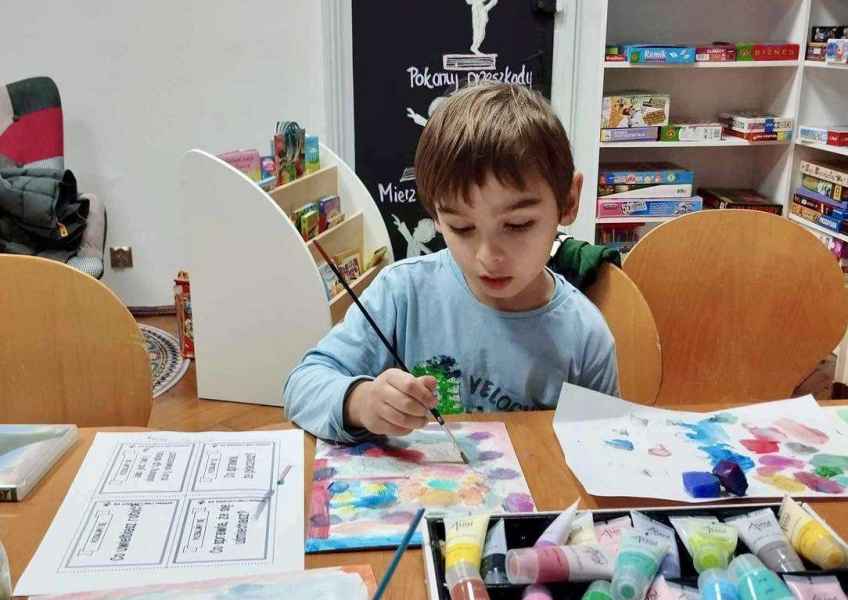 zdjęcie chłopca w trakcie malowania farbami