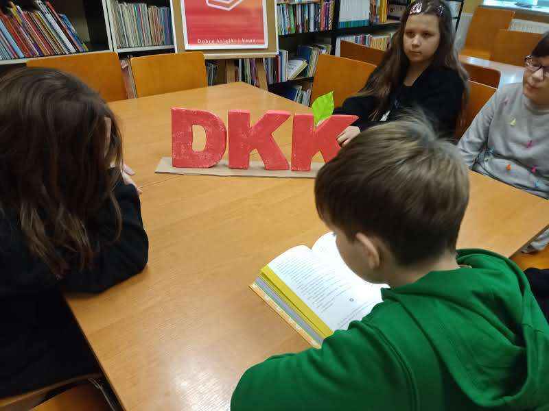 zdjęcie dziecka czytającego książkę przy stole wokół innych dzieci