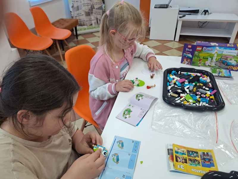 zdjęcie dziewczynek podczas układania modeli z klocków Lego przy stoliku