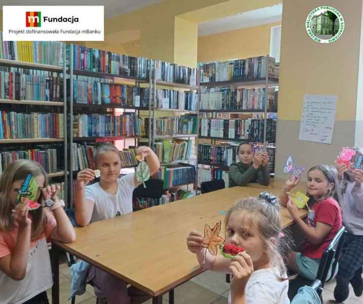 zdjęcie dzieci z własnymi pracami 3D przy stoliku, na górze logo biblioteki i mfundacji z napisem projekt dofinansowała fundacja mbanku
