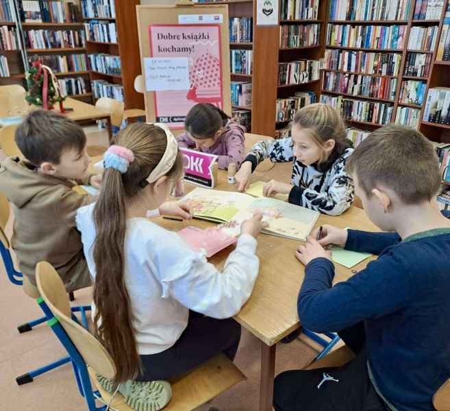 zdjęcie dzieci w trakcie czytania książki przy stoliku