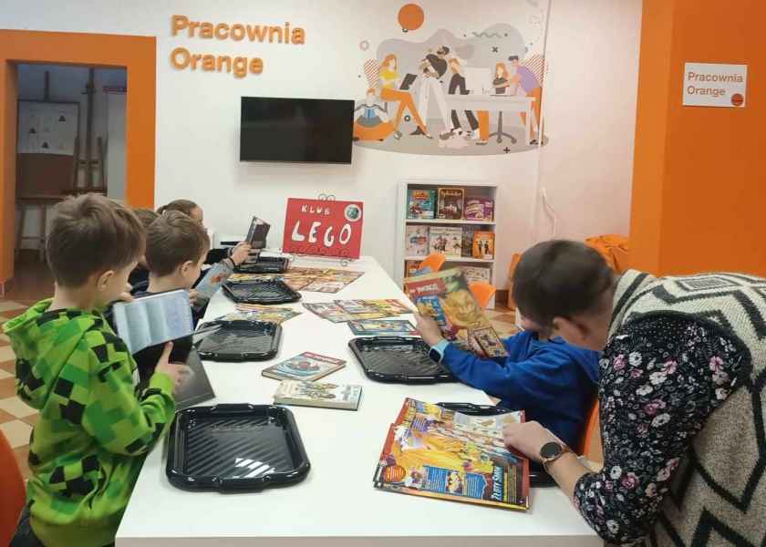 dzieci i bibliotekarka w trakcie przeglądania książek i czasopism o Lego