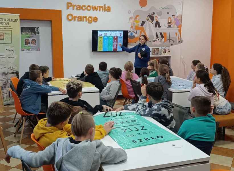 zdjęcie bibliotekarki podczas opowiadania dzieciom o segregacji przy telewizorze