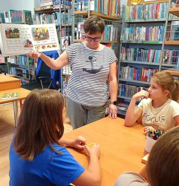 zdjęcie bibliotekarki pokazującej dzieciom elementarz Falskiego