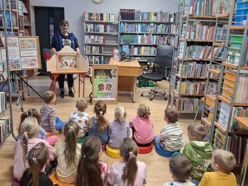 zdjęcie bibliotekarki z teatrzykiem i dzieci na pufach w bibliotece