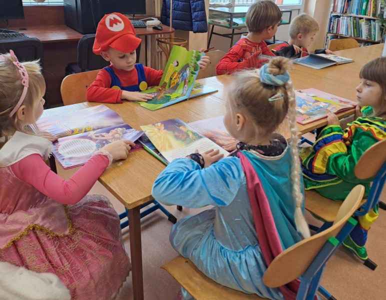 zdjęcie dzieci w bajkowych strojach oglądających bajki przy stoliku