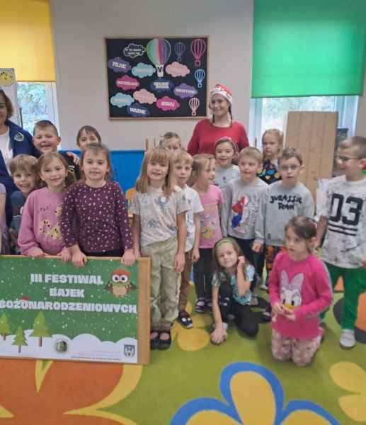 grupowe zdjęcie przedszkolaków trzymających plakat festiwalu z bibliotekarkami