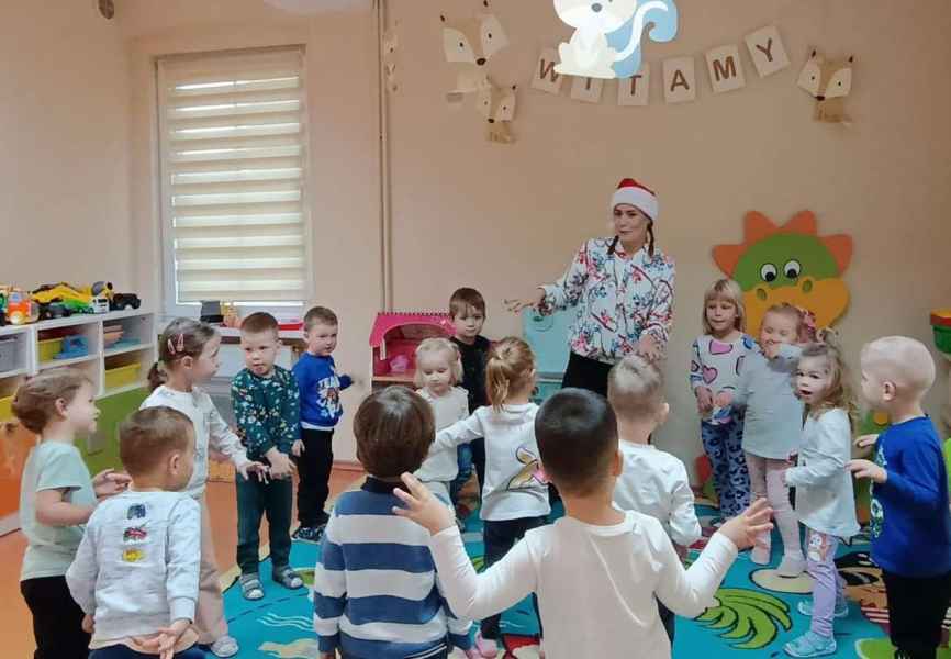 zdjęcie bibliotekarki w czapce mikołaja podczas zabawy z dziećmi w kółku