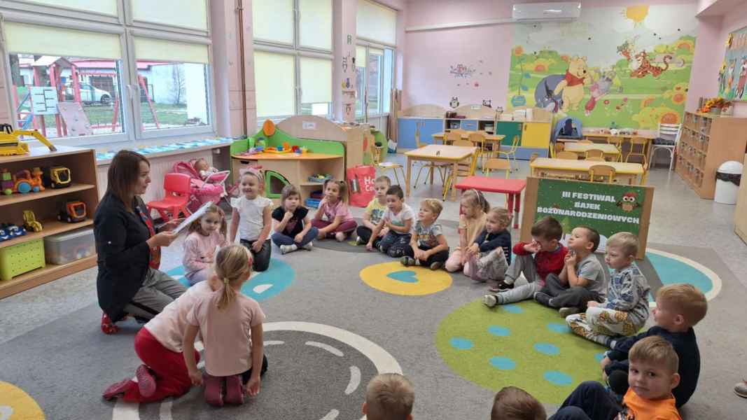 zdjęcie bibliotekarki czytającej dzieciom książkę na dywanie