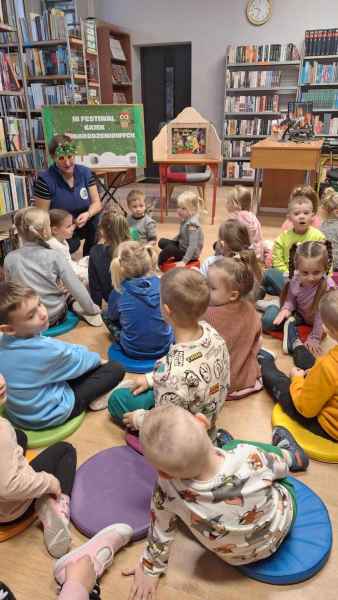 zdjęcie bibliotekarki w vhoinkowych okularach siedzącej obok i rozmawiającej z dziećmi