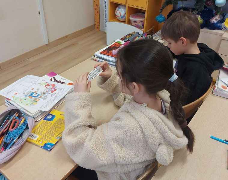 zdjęcie dwójki dzieci czytających karteczkę od bibliotekarki