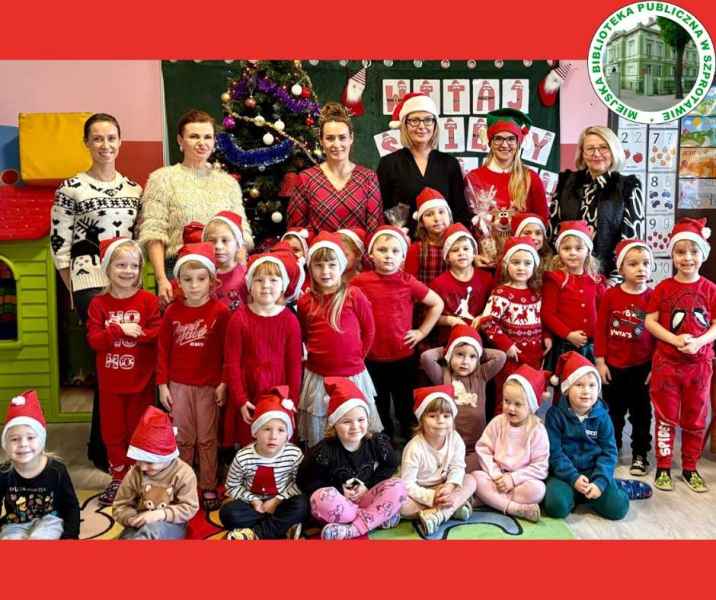 grupowe zdjęcie przedszkolaków w czapkach mikołaja, z wychowawcami, dyrektor i bibliotekarką, po prawej logo biblioteki