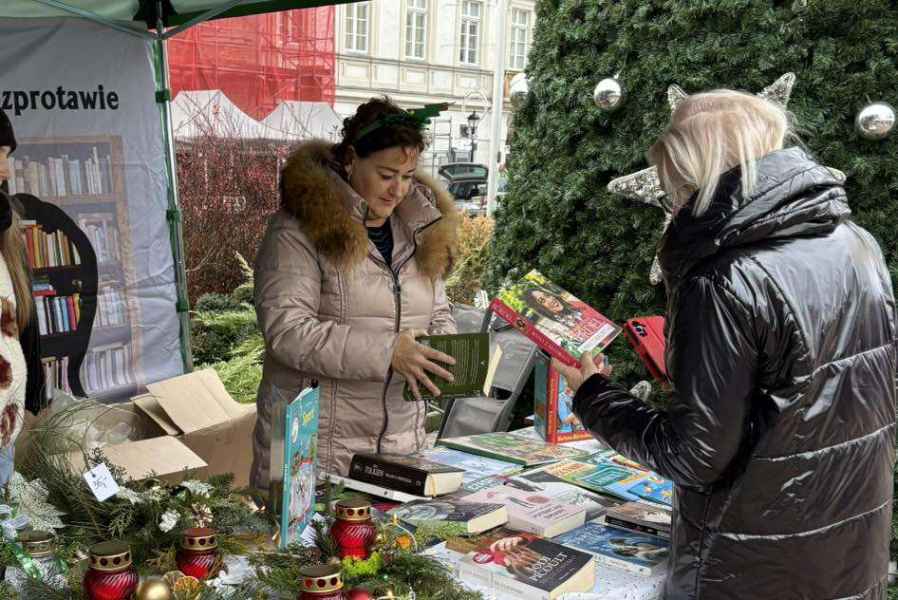 zdjęcie bibliotekarki i kobiety trzymających książki przy stoisku biblioteki