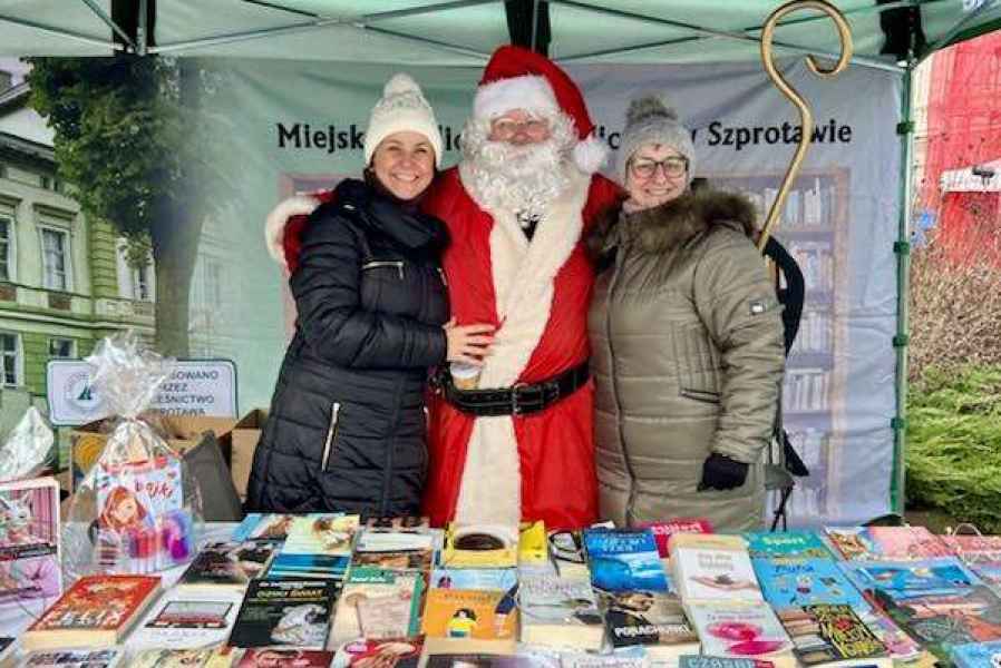 zdjęcie bibliotekarek przy stoisku biblioteki z mężczyzną w przebraniu Mikołaja