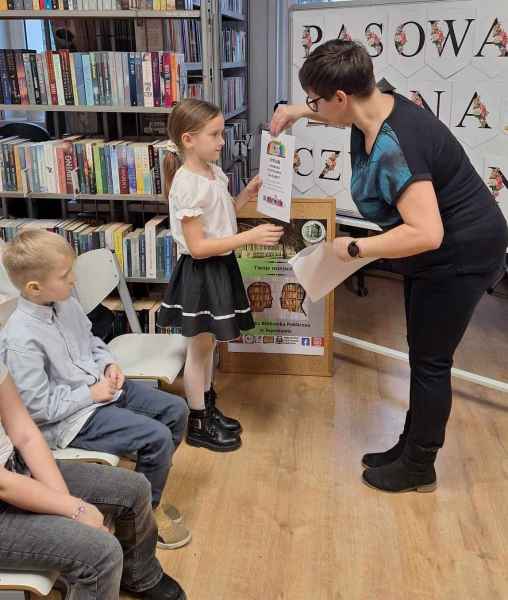 zdjęcie bibliotekarki wręczającej dziewczynce dyplom