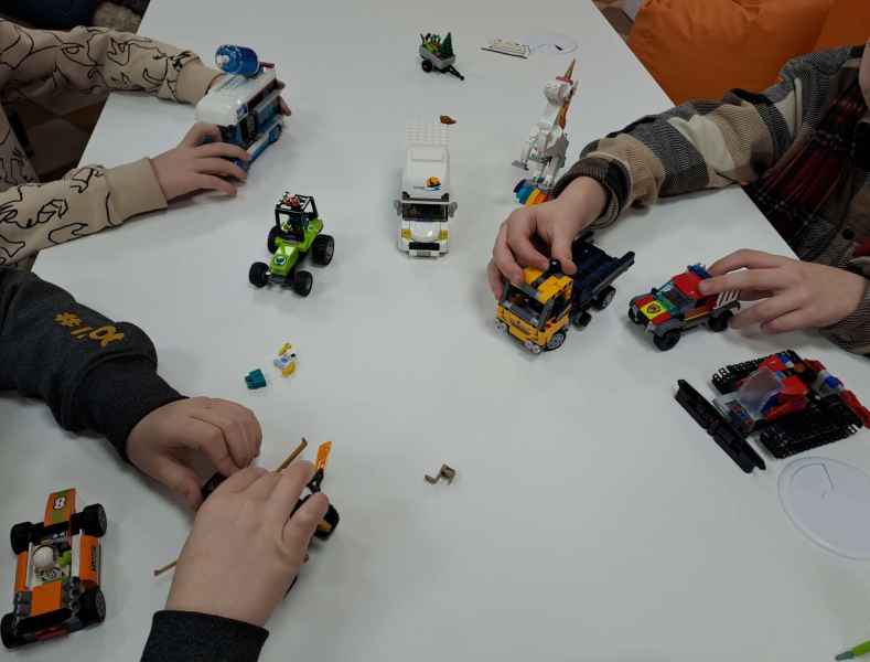 zdjęcie rąk dzieci podczas zabawy złożonymi modelami lego na stoliku