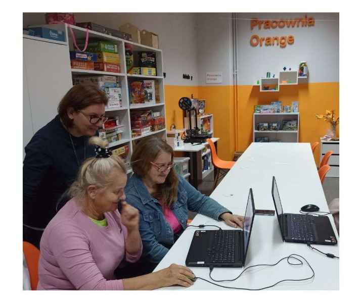 zdjęcie bibliotekarki stojącej za czytelniczkami przy laptopie