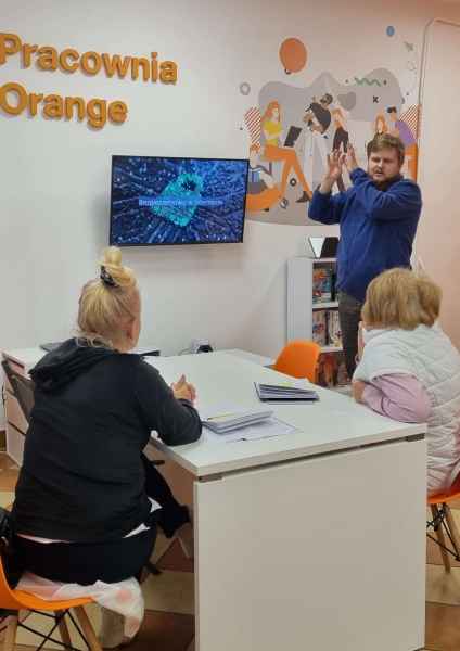 zdjęcie informatyka opowiadającego o internecie seniorkom w pracowni orange