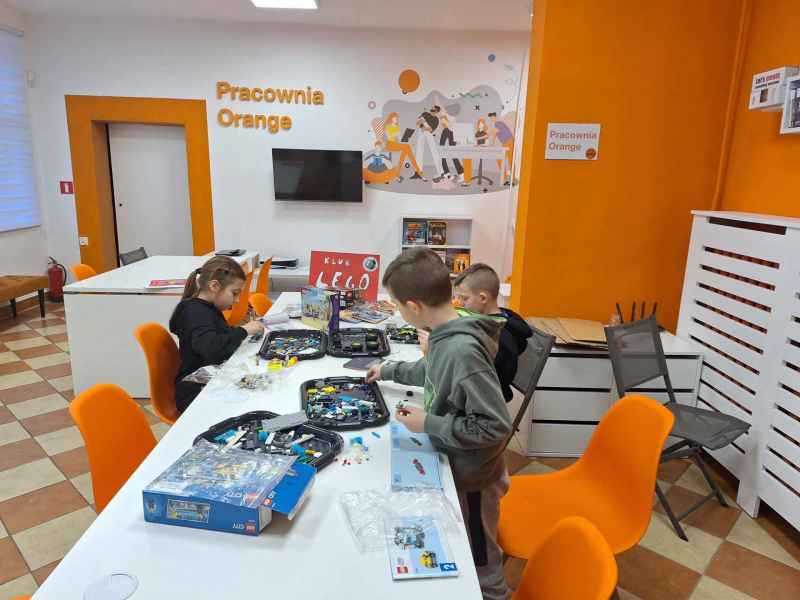 zdjęcie dzieci podczas składania modeli z klocków lego przy stoliku w pracowni orange