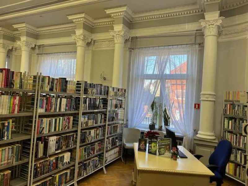 zdjęcie regałów z książkami, biurka i kolumn między oknami