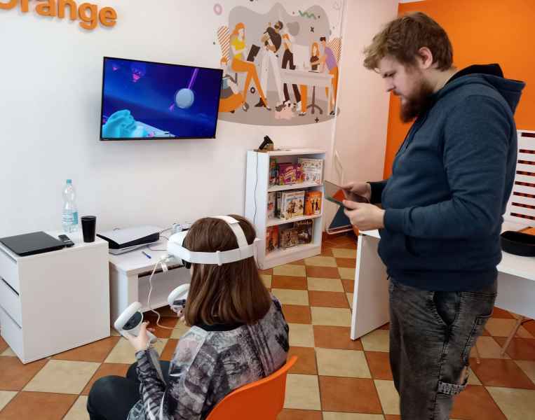 zdjęcie pracownika biblioteki przeprowadzającego dziewczynę  w goglach VR przez samouczek