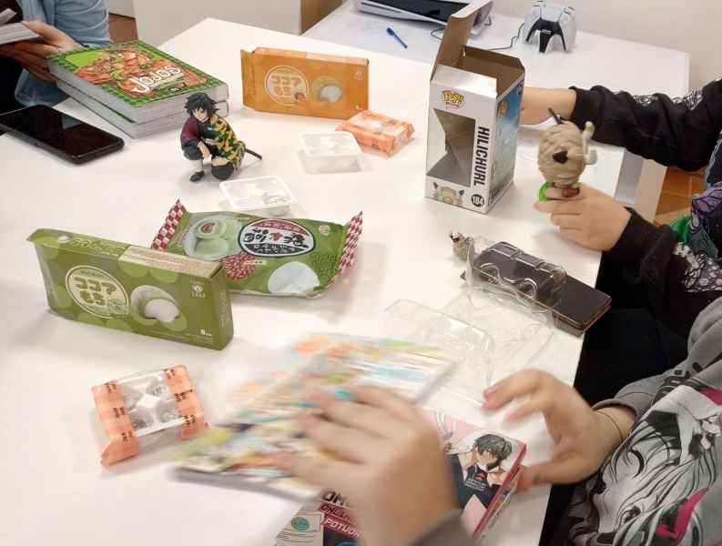 zdjęcie czytelniczek w trakcie oglądania mang i figurek, na stole smakołyk mochi