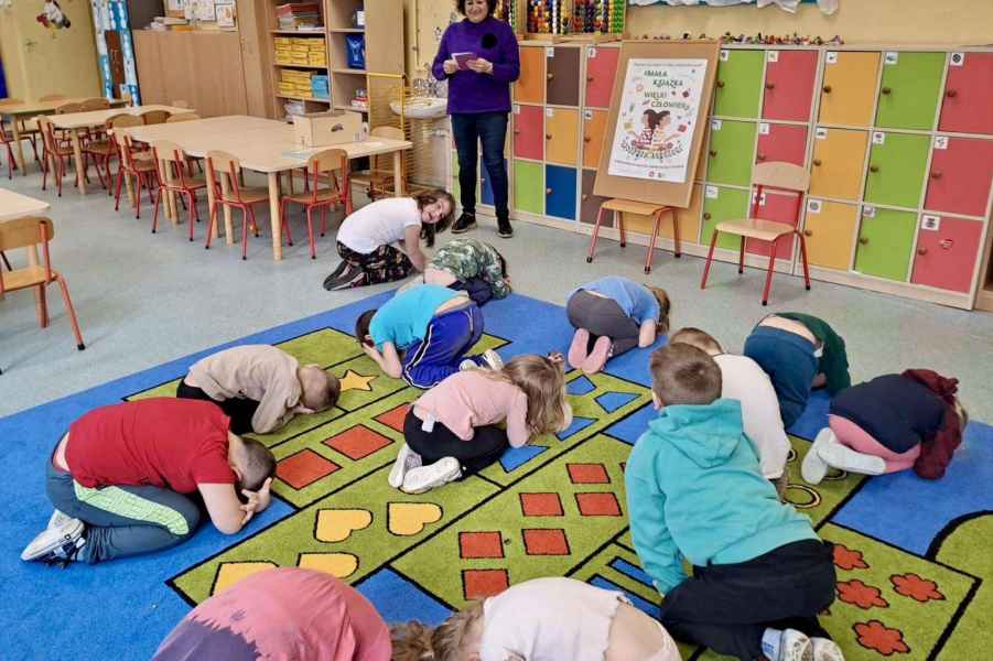 zdjęcie bibliotekarki i dzieci skulonych na dywanie jak żółw