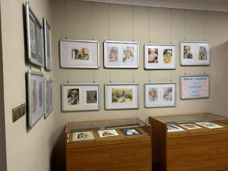 zdjęcie stojących gablot wystawowych oraz ściany z zawieszonymi obrazami nestorów