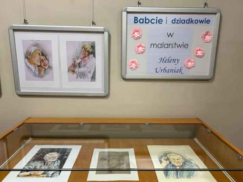 zdjęcie ściany i gabloty wystawowej z obrazami oraz napis babcie i dziadkowie w malarstwie Heleny Urbaniak