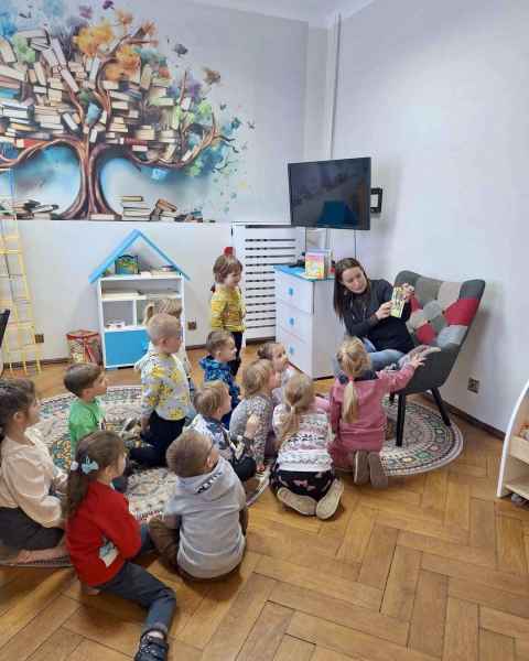 zdjęcie bibliotekarki pokazującej dzieciom książkę