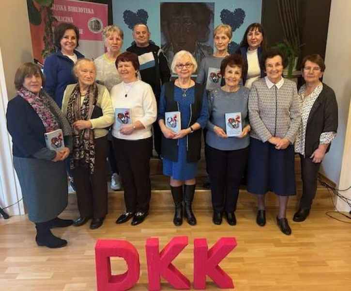 grupowe zdjęcie czytelniów i bibliotekarki przed nimi napis DKK