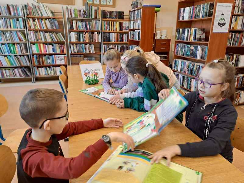 zdjęcie dzieci pokazujących sobie książeczki w bibliotece