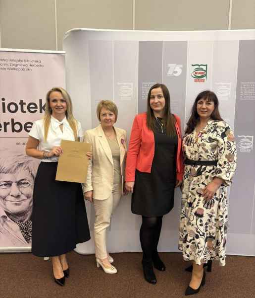 zdjęcie dyrektor biblioteki wraz z bibliotekarkami i odznaczeniami oraz dyplomem