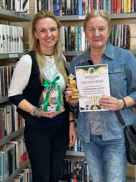 zdjęcie dyrektor biblioteki z nagrodą oraz czytelniczki ze statuetką i dyplomem na tle książek