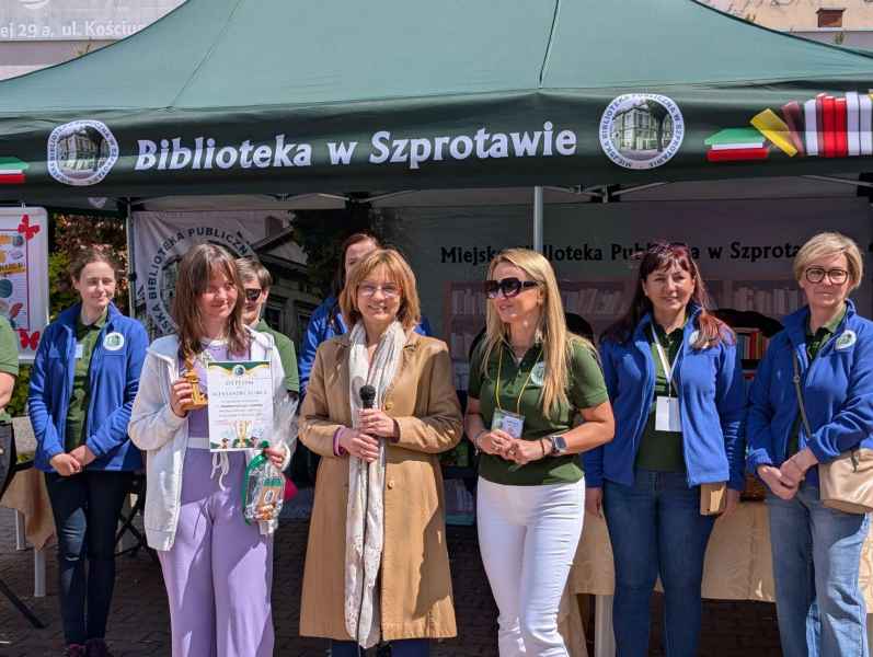 zdjęcie laureatki wraz z wiceburmistrz i dyrektor biblioteki na tle kadry biblioteki