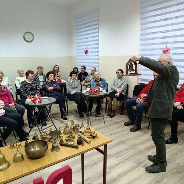 zdjęcie pana Łysakowskiego podczas prezentacji dzwonków ze swojej kolekcji czytelnikom przy stolikach