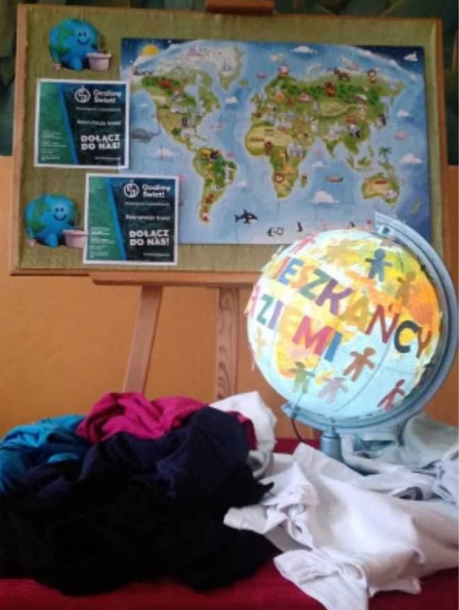 zdjęcie globusa i koszulek na tle mapy świata z logo projektu ocalimy świat i obrazkami kuli ziemskiej
