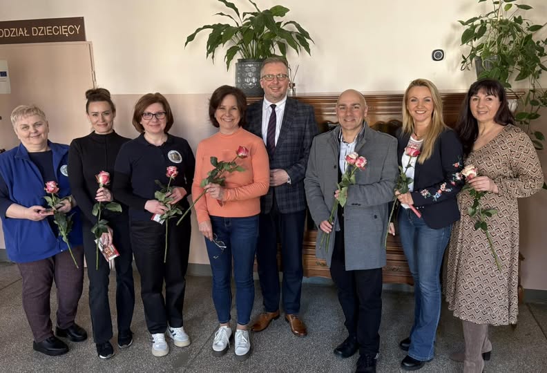 zdjęcie kadry biblioteki trzymającej róże i czekolady w towarzystwie burmistrza mirosława gąsika i kierownikiem wydziału promocji i turystyki macieja boryny